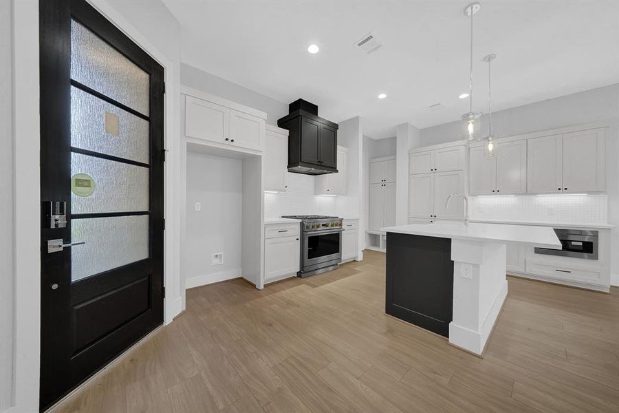 Kitchen cabinets are complete with matte black knobs and pulls. The Iron Ore venthood cabinet & kitchen island adds a striking contrast with it's deep, rich color.