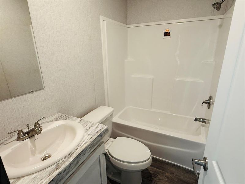 Full bath featuring toilet, vanity, shower / tub combination, and wood finished floors