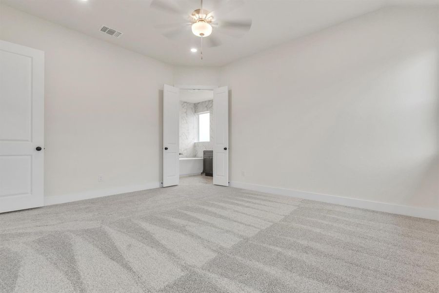 A spacious primary bedroom with plush carpeting opens to an en-suite bathroom, creating a serene retreat.
