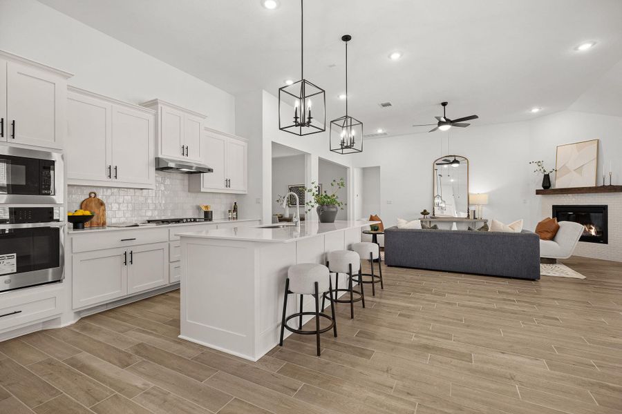 Kitchen featuring appliances with stainless steel finishes, open floor plan, pendant lighting, a kitchen bar, and a center island with sink
