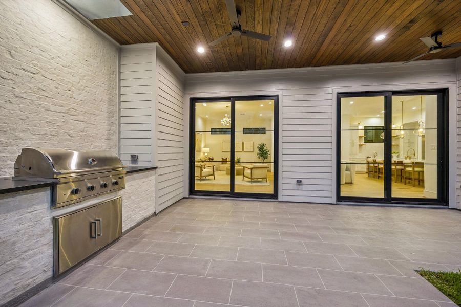 Large covered Lanai with a Built-In Stainless Steel Grill, Slab Granite Counter and Two Stainless Steel Doors that lead to under counter storage.  The Lanai ceiling is finished with Tongue and Groove Stained Wood and Two Ceiling Fans. The patio floor is completed with a stamped smooth texture concrete.