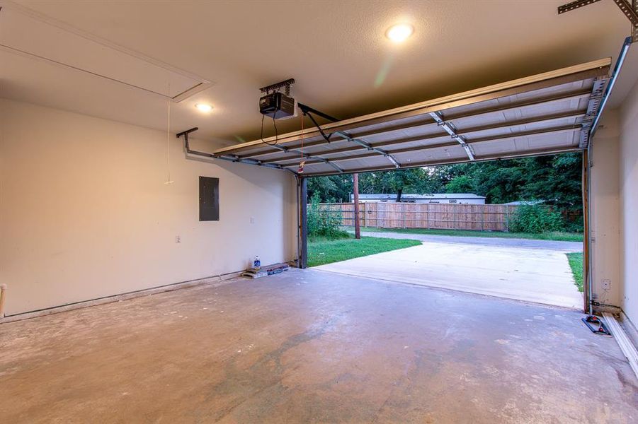 Garage with electric panel, a garage door opener, and recessed lighting Garage with electric panel, a garage door opener, and recessed lighting