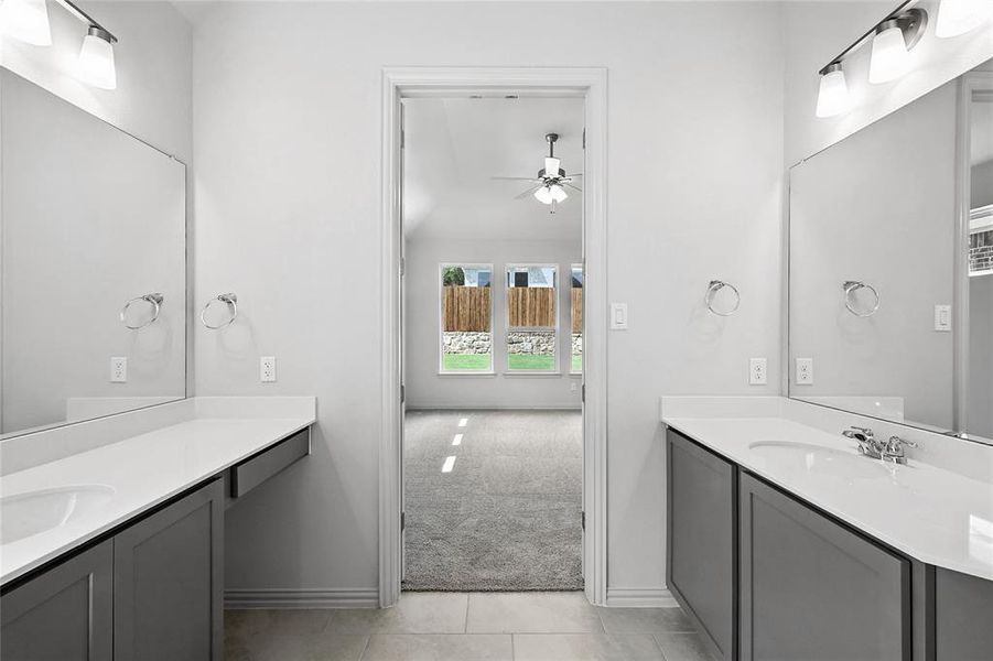 Bathroom featuring ceiling fan, two vanities, tile patterned floors, and lofted ceiling Bathroom featuring ceiling fan, two vanities, tile patterned floors, and lofted ceiling