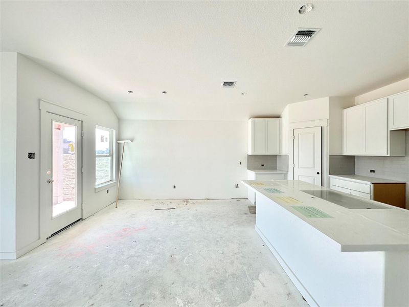 Kitchen with white cabinets, electric cooktop, a kitchen island, and decorative backsplash