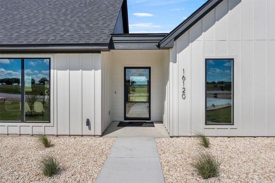 View of exterior entry featuring board and batten siding and a shingled roof View of exterior entry featuring board and batten siding and a shingled roof
