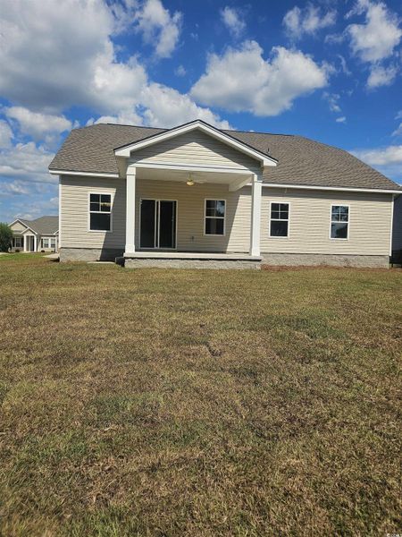 Back of property featuring a lawn, a patio area, and roof with shingles