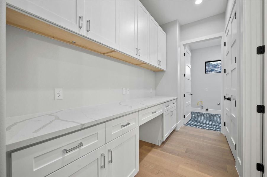 Interior space with white cabinets, light hardwood / wood-style flooring, and light stone counters
