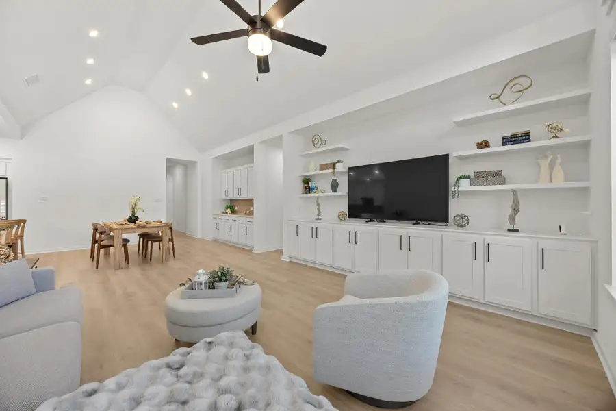Living area featuring light wood finished floors, ceiling fan, and a high ceiling