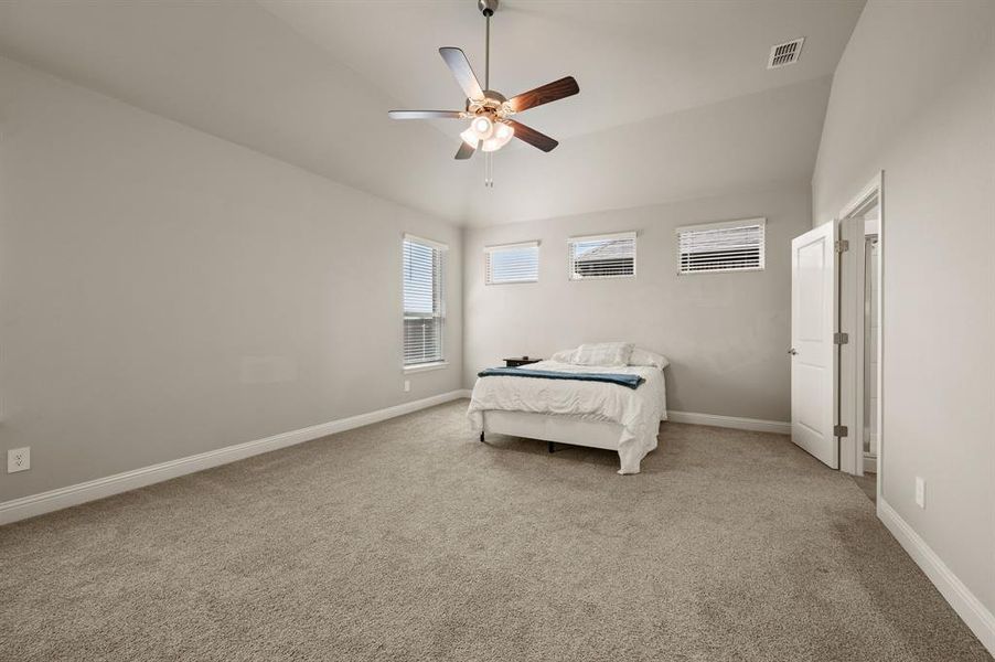 Wide view of the primary suite emphasizing its generous size, multiple windows, and serene atmosphere.