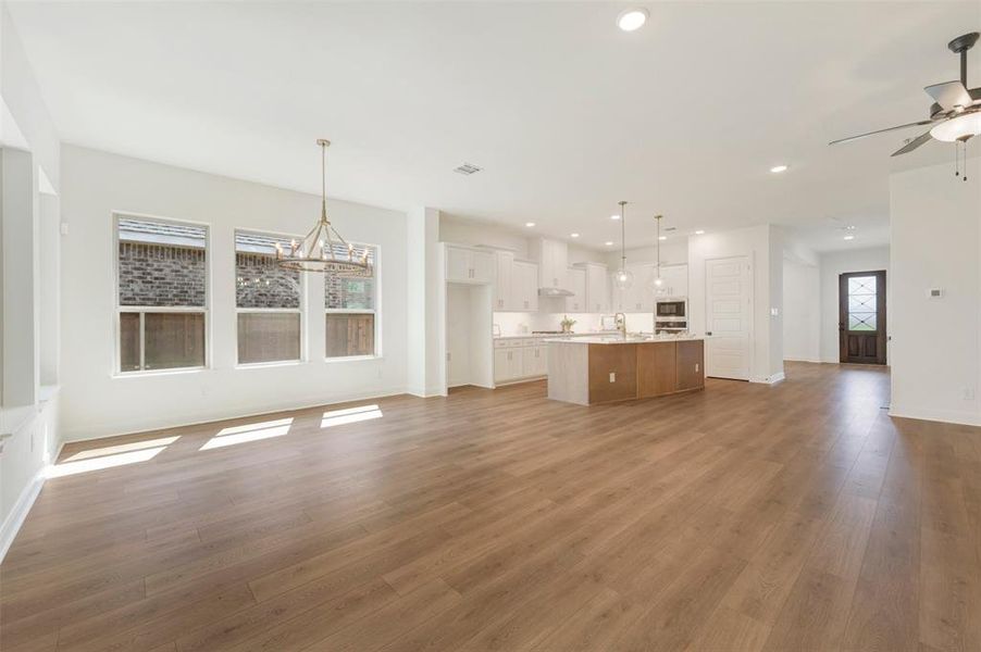 Spacious open-concept interior featuring wood-finish flooring, recessed lighting, and a modern kitchen with a large island Spacious open-concept interior featuring wood-finish flooring, recessed lighting, and a modern kitchen with a large island