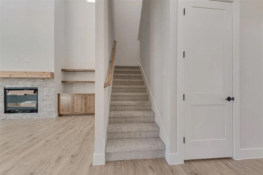 Stairway with wood finished floors and a fireplace