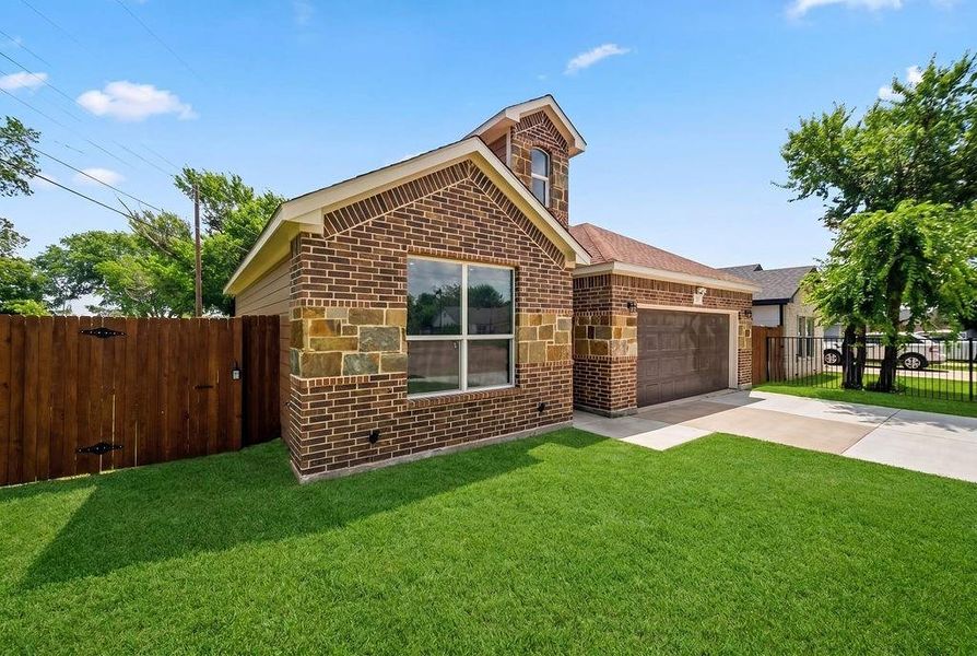 Brick and stone facade featuring a prominent front window, an attached garage with a dark-finish door, and a concrete driveway Brick and stone facade featuring a prominent front window, an attached garage with a dark-finish door, and a concrete driveway