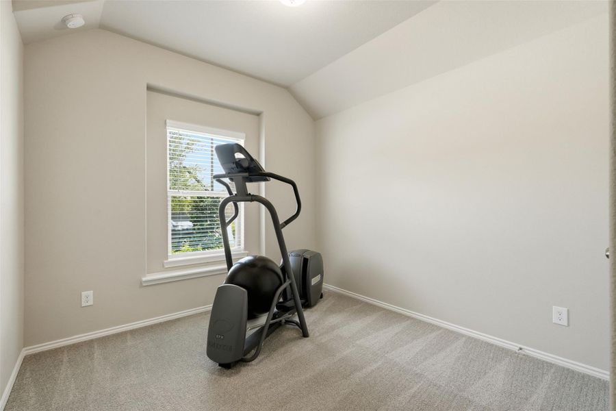 This room is bright and cozy, featuring a large window with blinds and neutral walls. Currently set up as a home gym, it offers potential for a bedroom or office. Carpeted flooring adds comfort. This room is bright and cozy, featuring a large window with blinds and neutral walls. Currently set up as a home gym, it offers potential for a bedroom or office. Carpeted flooring adds comfort.