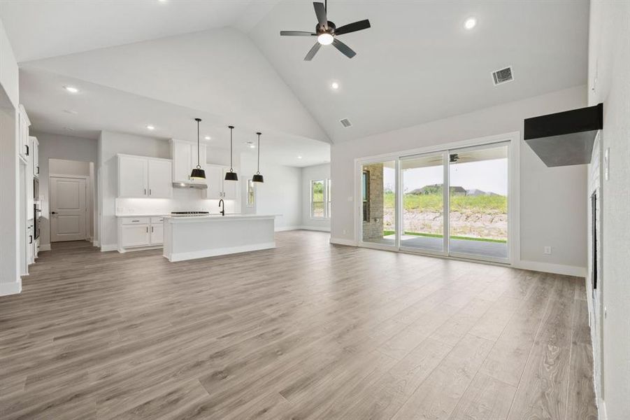 Unfurnished living room with high vaulted ceiling, a ceiling fan, light wood-style flooring, and recessed lighting