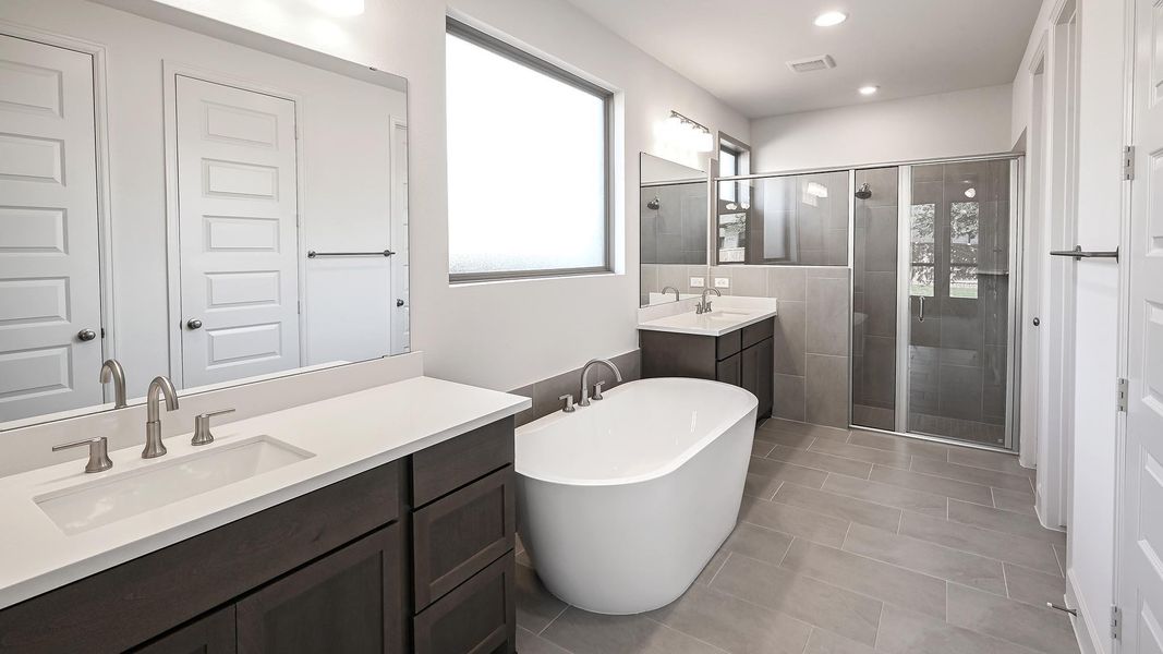 Bathroom featuring a stall shower, a freestanding tub, two vanities, and light tile patterned floors Bathroom featuring a stall shower, a freestanding tub, two vanities, and light tile patterned floors