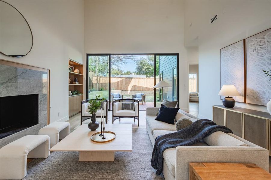 Living room featuring hardwood / wood-style floors, a towering ceiling, and a high end fireplace