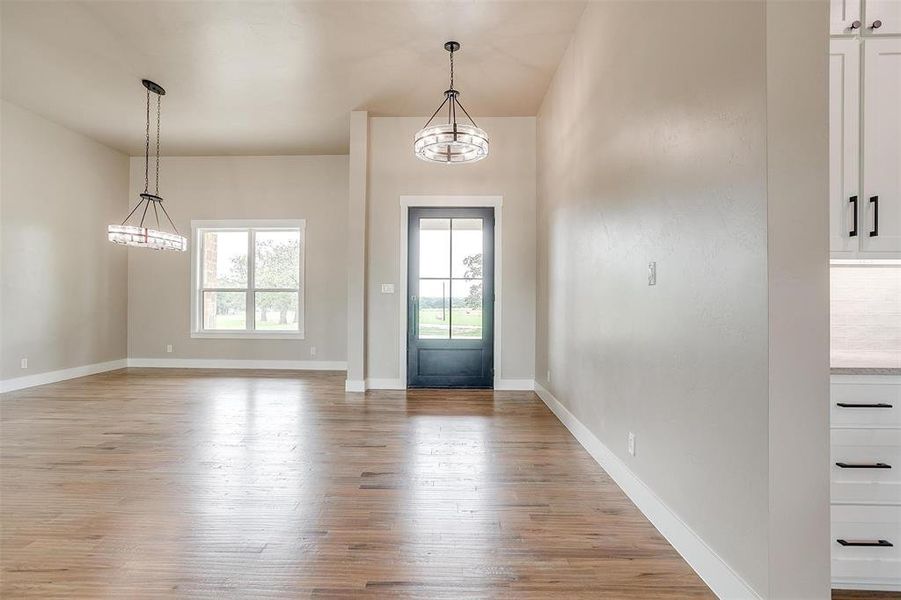 Foyer with a chandelier, light wood-type flooring, and baseboards Foyer with a chandelier, light wood-type flooring, and baseboards