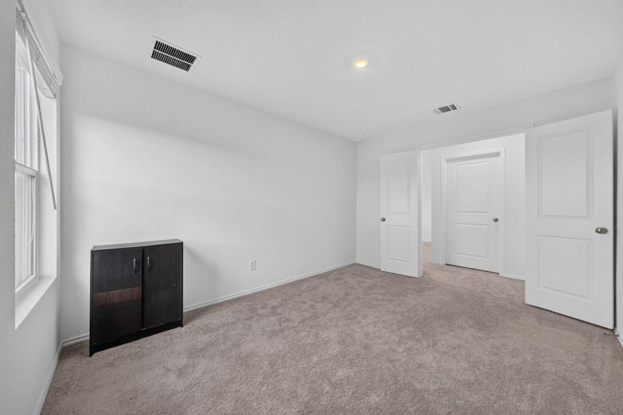 A well-lit bedroom features plush carpeting and multiple doorways leading to adjoining spaces. A well-lit bedroom features plush carpeting and multiple doorways leading to adjoining spaces.