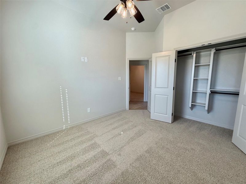 Unfurnished bedroom featuring light carpet, a closet, ceiling fan, and a towering ceiling