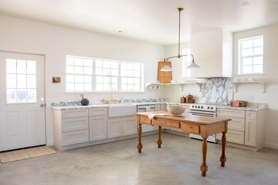 Kitchen with slide in range oven, concrete flooring, stainless steel dishwasher, decorative backsplash, and decorative light fixtures Kitchen with slide in range oven, concrete flooring, stainless steel dishwasher, decorative backsplash, and decorative light fixtures