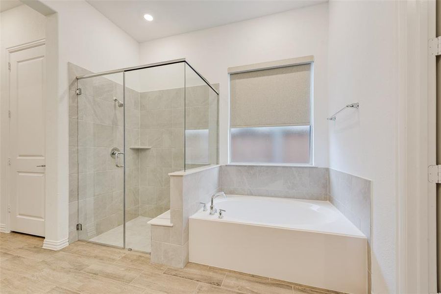 Bathroom featuring a bath, a stall shower, wood finished floors, and recessed lighting Bathroom featuring a bath, a stall shower, wood finished floors, and recessed lighting