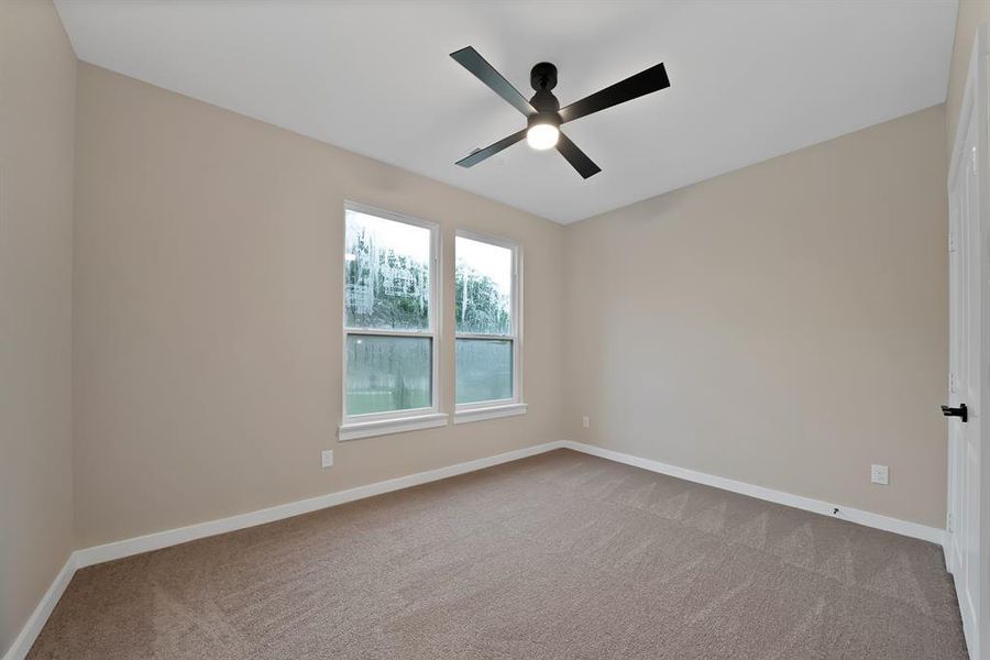 Neutral-toned room with two windows, carpet flooring, and a ceiling fan Neutral-toned room with two windows, carpet flooring, and a ceiling fan