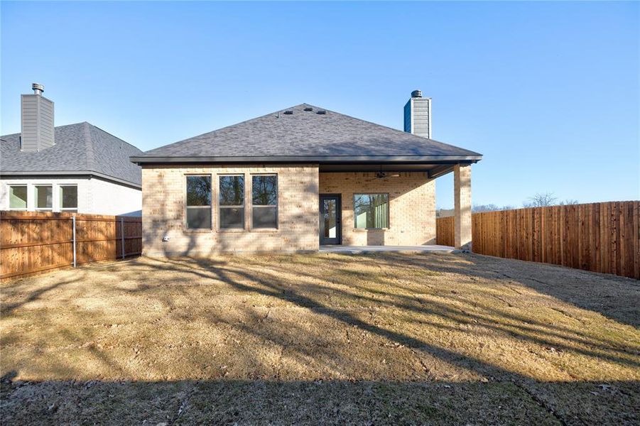 Rear view of house featuring ceiling fan, a yard, and a patio