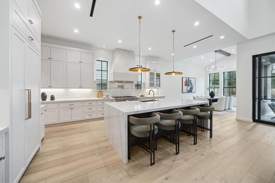 A chef’s dream kitchen featuring custom cabinetry, a large island with a marble countertop, and designer pendant lighting. High-end Thermador appliances complete the elegant and functional design.