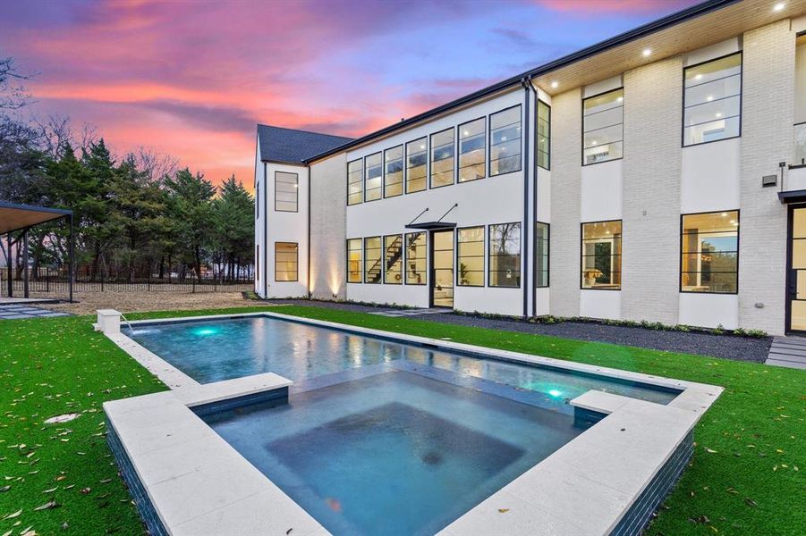 Pool at dusk featuring an in ground hot tub and a yard