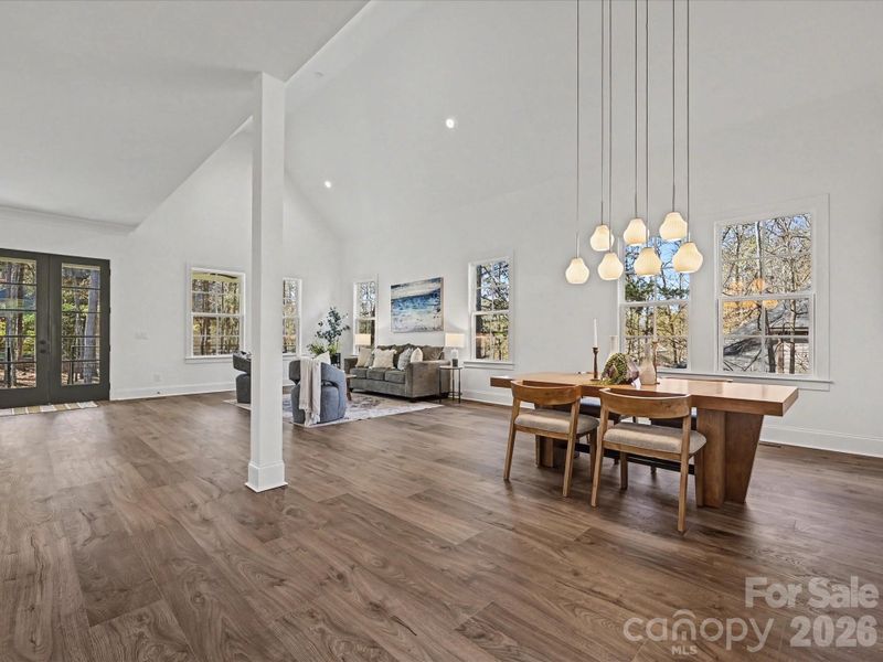 Light-filled great room and dining area with soaring ceilings, expansive windows, and an open-concept layout perfect for entertaining and everyday living.