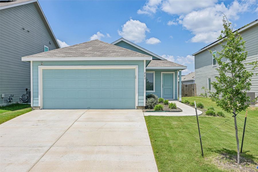 Single-story residence featuring a two-car garage with a light blue door, a gray shingled roof, a paved driveway, and a concrete walkway to the front entry Single-story residence featuring a two-car garage with a light blue door, a gray shingled roof, a paved driveway, and a concrete walkway to the front entry