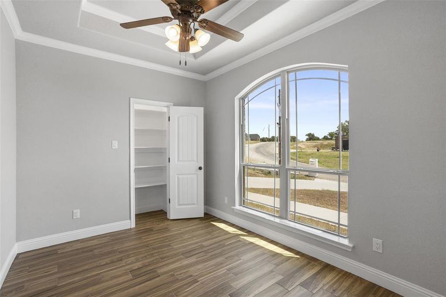 Unfurnished bedroom with ceiling fan, hardwood / wood-style flooring, ornamental molding, and a closet