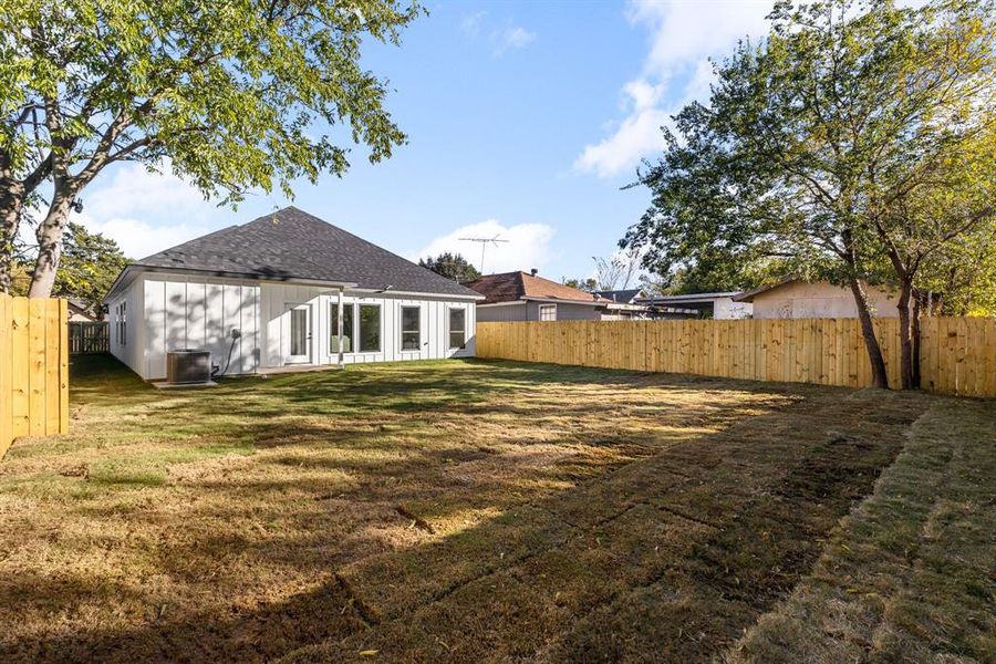 Rear view of property with a lawn and central air condition unit