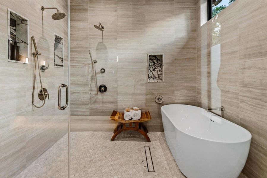 Walk in shower with dual heads, custom marble niches, and soaking tub.