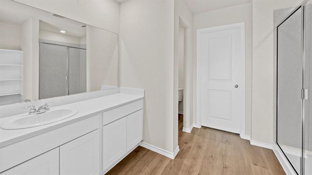 Full bath with a shower stall, vanity, and light wood finished floors