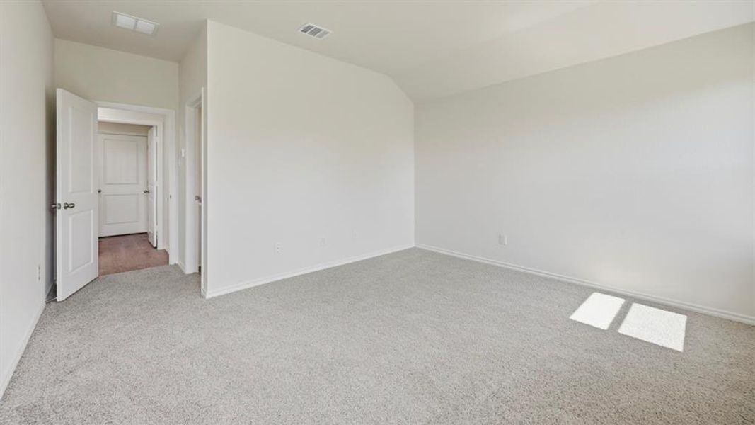 Empty room with light carpet and vaulted ceiling