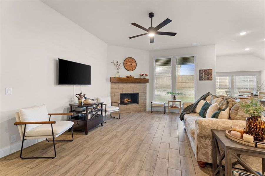 Living area featuring light wood-type flooring, a stone fireplace, recessed lighting, a ceiling fan, and vaulted ceiling Living area featuring light wood-type flooring, a stone fireplace, recessed lighting, a ceiling fan, and vaulted ceiling
