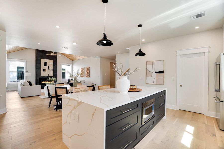 The open concept living area features light hardwood flooring and a vaulted ceiling with exposed wood paneling The open concept living area features light hardwood flooring and a vaulted ceiling with exposed wood paneling