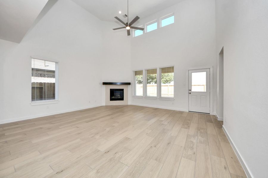 Welcome family and guests to your charming living room! With its high ceilings, recessed lighting, ceiling fan, custom paint, beautiful flooring, and large windows that let in abundant natural light, this room is perfect for gatherings. Sample photo of completed home with similar floor plan. Actual colors and selections may vary.