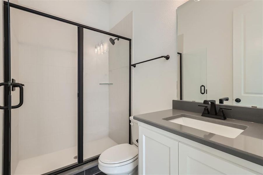 Bathroom with an enclosed shower, toilet, and vanity