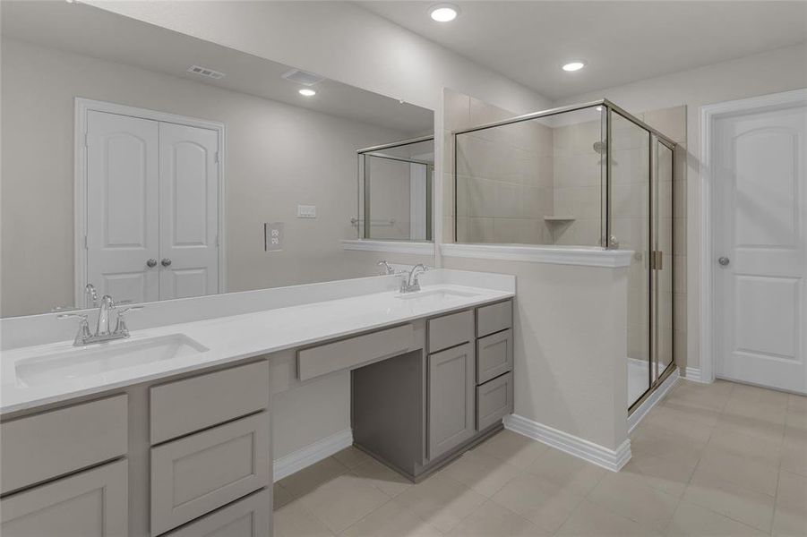 Primary spacious restroom, very modern featuring a long double vanity with ample storage, a large mirror, and a glass-enclosed shower. It has a neutral color palette and is well-lit with recessed lighting.