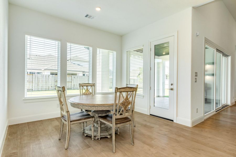 Spacious dining area featuring oversized windows that flood the room with natural light and offer a clear view of the backyard, complemented by a single door providing seamless access to the covered patio