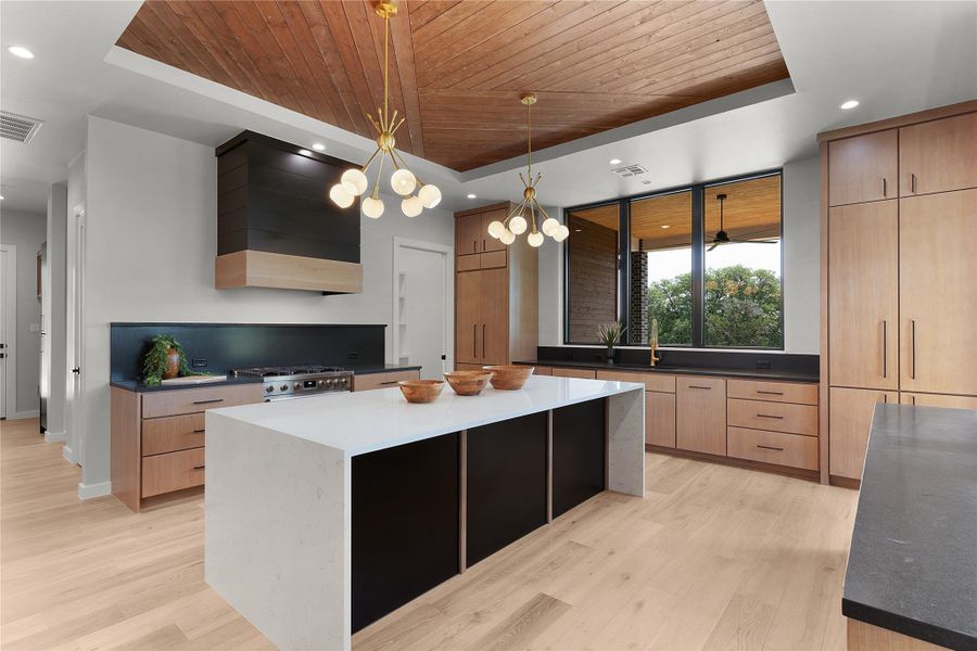 Kitchen featuring a raised ceiling, wooden ceiling, wall chimney exhaust hood, modern cabinets, and light wood floors Kitchen featuring a raised ceiling, wooden ceiling, wall chimney exhaust hood, modern cabinets, and light wood floors