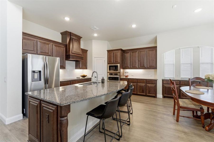 Kitchen with a kitchen bar, light stone countertops, dark wood finish cabinets, and recessed lighting