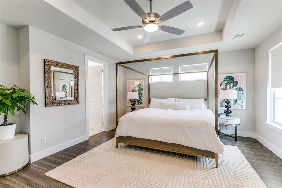 Bedroom with wood-type flooring, a raised ceiling, and ceiling fan