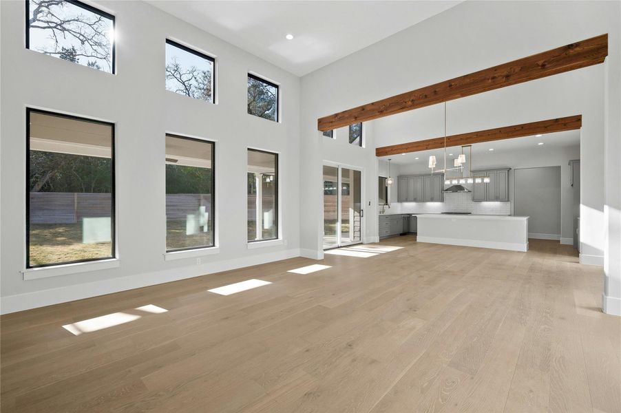 Unfurnished living room with a towering ceiling and light wood-type flooring