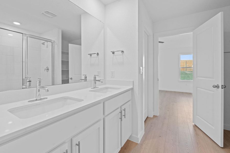 Bathroom with light wood-type flooring, double vanity, and a shower stall