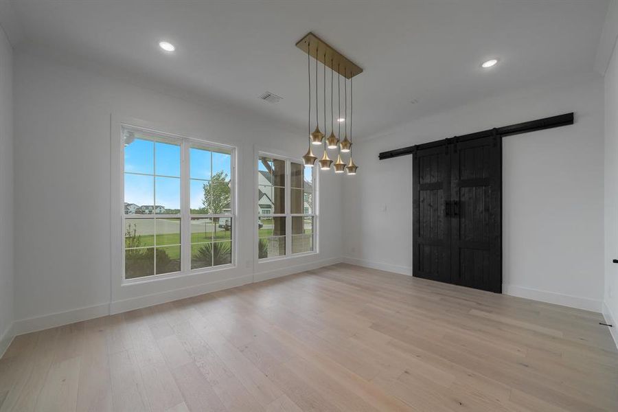 Unfurnished dining area featuring light hardwood / wood-style floors and a barn door