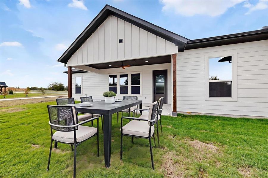 Rear view of house with a yard, a patio area, board and batten siding, and a ceiling fan