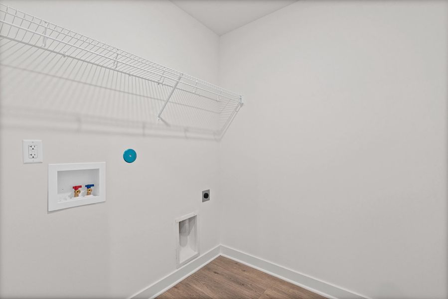 Laundry area featuring a wire shelving unit, wood-finish flooring, and crisp white walls